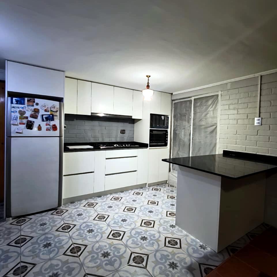 Cocina blanca con cubierta de cuarzo negro y piso hidráulico